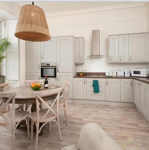 a kitchen with a table and chairs and a kitchen with white cabinets at Stylish Town Apt in Hawick