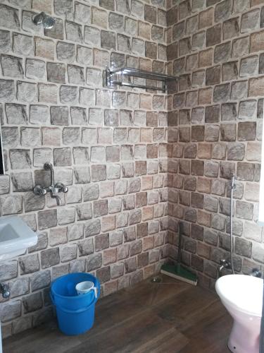 a bathroom with a brick wall with a sink and a toilet at Café The Wall in Pushkar