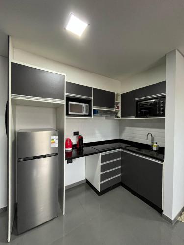 a kitchen with black and white cabinets and a stainless steel refrigerator at Departamento entero en San Lorenzo in San Lorenzo
