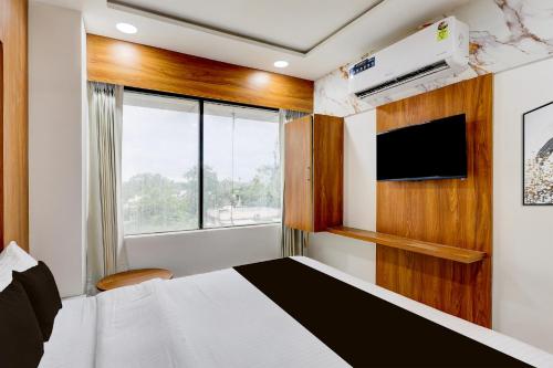 a bedroom with a bed and a tv and a window at Hotel O Dream Space in Ahmedabad