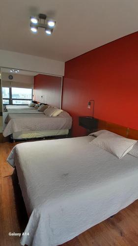 two beds in a room with a red wall at Mía Apart in Buenos Aires