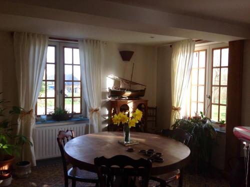 - une salle à manger avec une table et des fleurs dans l'établissement L'Orchard, à Bonneville-la-Louvet