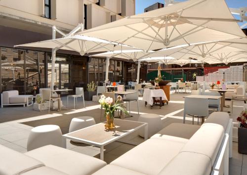 a patio with white tables and chairs and umbrellas at Mercure Montpellier Centre Comédie in Montpellier
