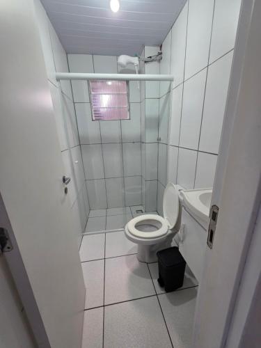 a white bathroom with a toilet and a sink at Pousada Buenos Aires in Pontal do Paraná