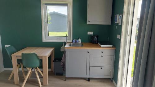 a kitchen with a sink and a table and a window at Recreatie aan de Vecht, Hooibergje 3, Weesp in Weesp