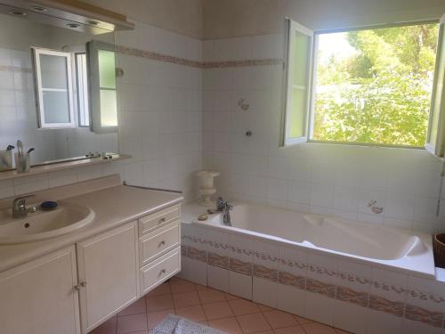 a bathroom with a tub and a sink and a window at Villa avec jardin et piscine 3 minutes de la Rochelle in Lagord