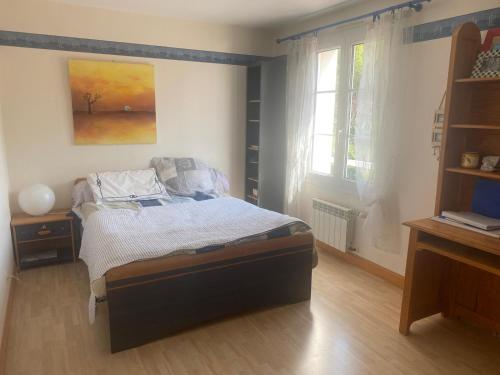 a bedroom with a bed and a desk and a window at Villa avec jardin et piscine 3 minutes de la Rochelle in Lagord