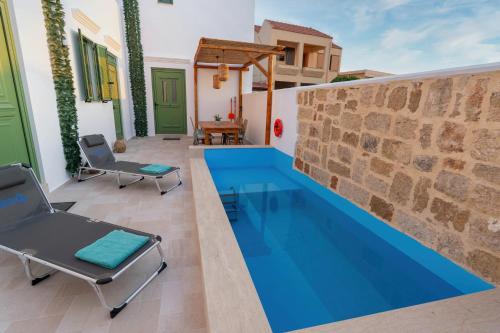 a pool in a house with two chairs next to it at Villa Emerald in Koskinou