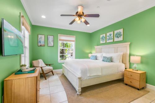 1 dormitorio con paredes verdes y 1 cama con ventilador de techo en SUGAR PALM SUITE at Travelers Palm Inn Key West, en Key West