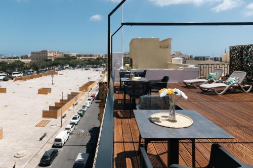 a balcony with a table and chairs on a roof at Florette Suite Designer Finish with Stunning Lounge Terrace by ArcoBnb in Il-Furjana