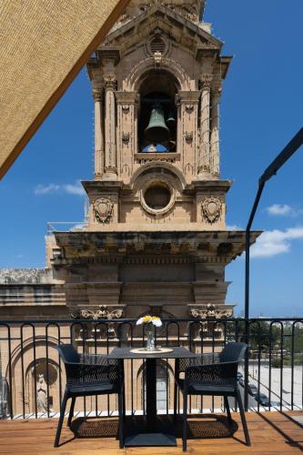 a clock tower with a table and two chairs at Florette Suite Designer Finish with Stunning Lounge Terrace by ArcoBnb in Il-Furjana