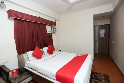 a bedroom with a large white bed with red pillows at Hotel O Relax in Gwalior