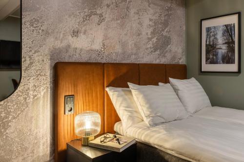 a bedroom with a bed and a table with a lamp at H28 - Hotel, Apartments and Suites by UHANDA in Tampere