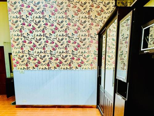 a room with a wall with a floral wallpaper at สวนไมตรีจิต รีสอร์ท in Ban Khlong Si