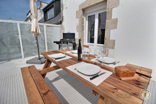 a wooden table with plates and wine glasses and a piano at Ti ma zud 2 in Plestin-les-Grèves