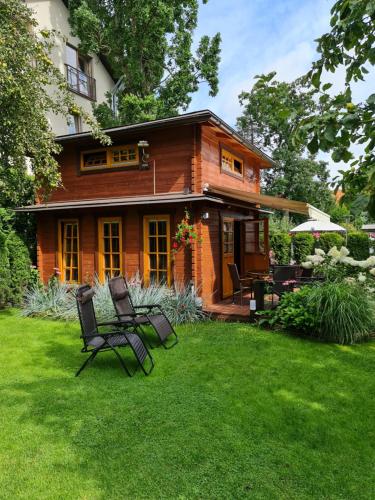 a wooden house with two chairs in the yard at Viešnagė Palangoje pas J&I in Palanga