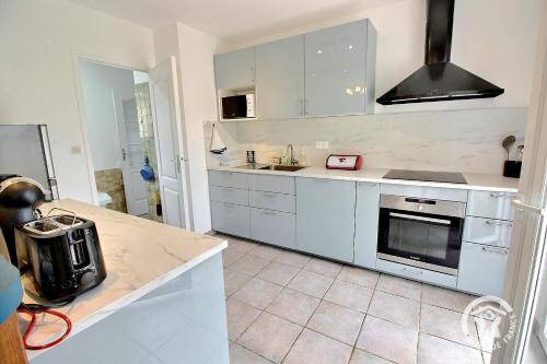 a kitchen with white cabinets and a stove top oven at Ker hevoudek in Étables-sur-Mer