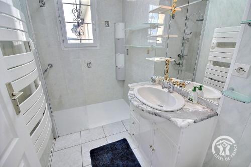 a white bathroom with a sink and a shower at Ker hevoudek in Étables-sur-Mer