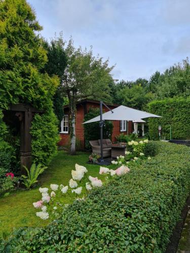 a garden with an umbrella and flowers in front of a house at Viešnagė Palangoje pas J&I in Palanga