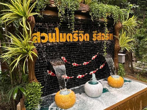 three fountains in front of a sign with plants at สวนไมตรีจิต รีสอร์ท in Ban Khlong Si