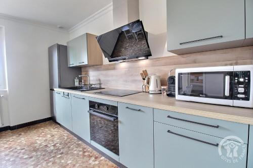 a kitchen with white cabinets and a microwave oven at D'azeline in Lamballe Armor