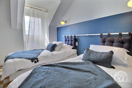 a bedroom with two beds and a blue wall at D'azeline in Lamballe Armor