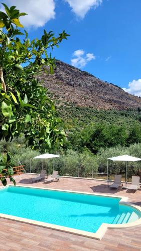 a swimming pool with chairs and umbrellas next to a hill at Villa MaVi Guesthouse in Maenza