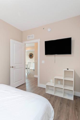 a bedroom with a bed and a flat screen tv on a wall at The Perch 14 on Front 2BR Private Hot Tub Patio Downtown Walks in Traverse City