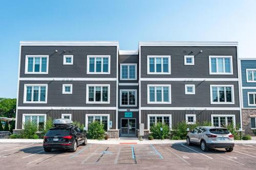 a large building with two cars parked in a parking lot at The Perch 14 on Front 2BR Private Hot Tub Patio Downtown Walks in Traverse City