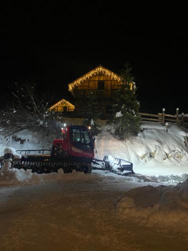 a red truck is pulling a snowmobile in front of a house at Eirl DOLOMITES Retreat Sappada in Sappada