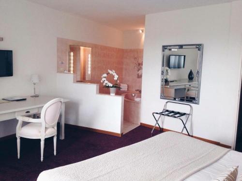 a bedroom with a bed and a desk and a mirror at Relais Du Vignoble in Gueberschwihr