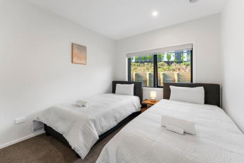 two beds in a room with a window at Kinloch Lookout in Kinloch