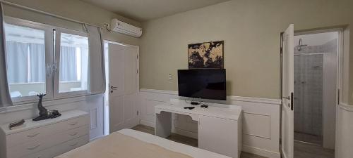 a white bathroom with a television and a white desk at Vilas Praia de Chaves Sol & Mar in Cabeçadas