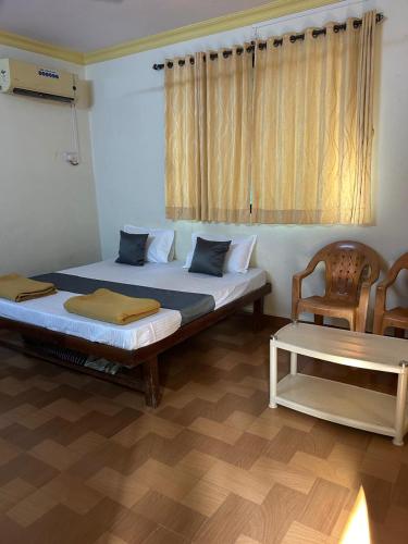 a bedroom with two beds and a chair and a table at Vartak wadi smita villa in Nagaon