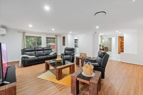 a living room with black leather furniture and a table at Nature Escape Acreage Forest Life and Pet Friendly in Boronia Heights