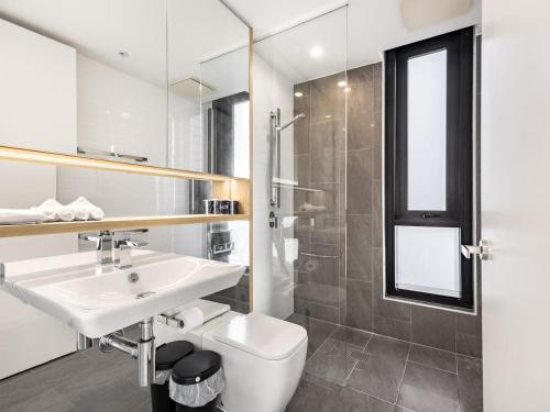 a bathroom with a sink and a toilet and a mirror at Stylish 2BR Unit with Pool and Gym in South Brisbane in Brisbane