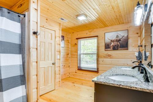 un bagno in stile baita di tronchi con lavandino e doccia di River Escape River Front Cabin a Tellico Plains
