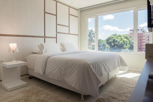 a white bedroom with a large bed and a window at Hub Hotel Asuncion in Asuncion