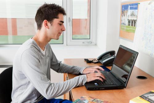 a man sitting at a desk using a laptop computer at University of Toronto-New College Residence-45 Willcocks Residence in Toronto