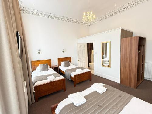 a bedroom with two beds and a chandelier at Sandyford Lodge in Glasgow