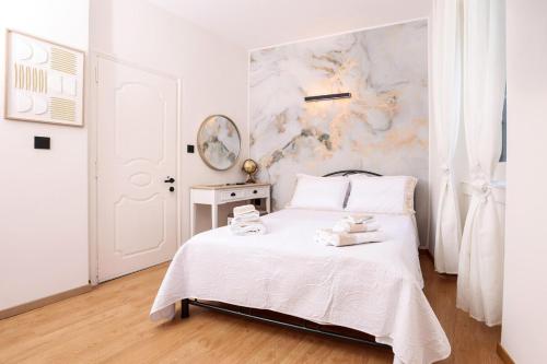a white bedroom with a bed and a wall at Luce al Centro in Corfu
