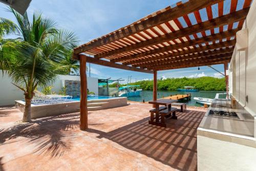 a patio with a wooden pergola and a table at Marina Comodoro in Isla Mujeres