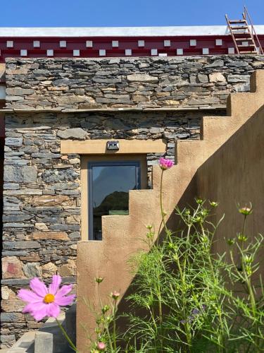 a stone house with a window and some flowers at Bamei Sonam Farm in Qianning