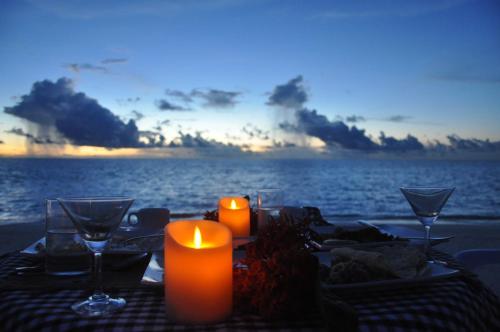 a table with candles and wine glasses on the beach at Rasdhoo Coralville in Rasdu