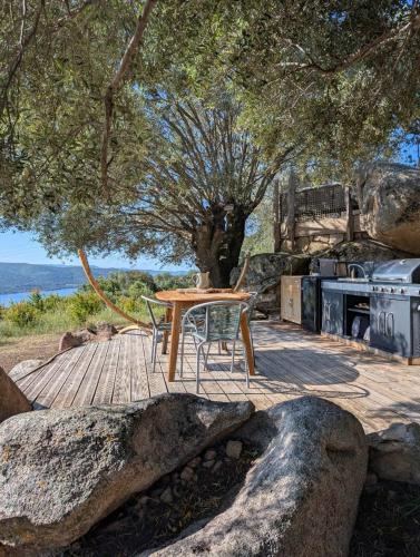 a wooden table and chairs on a patio with a stove at A Malgrana - Tente lodge hébergement insolite in Coti-Chiavari