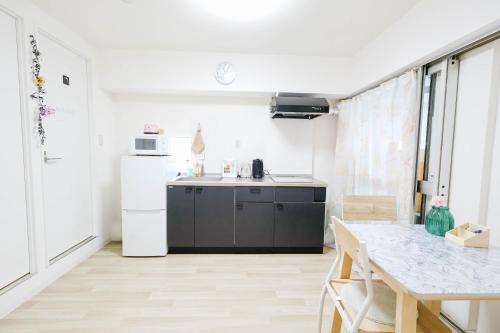 a kitchen with a table and a white refrigerator at Shinjuku Kabuki Youth Hostel#New Sunshine Room#50 second walk from Higashi Shinjuku subway#Automatic locking door at entrance in Tokyo