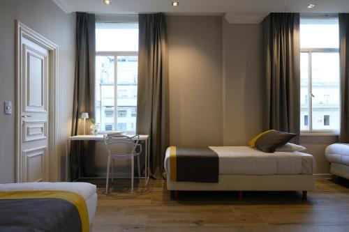 a hotel room with two beds and a table and window at Midtown Boutique Hotel in Buenos Aires