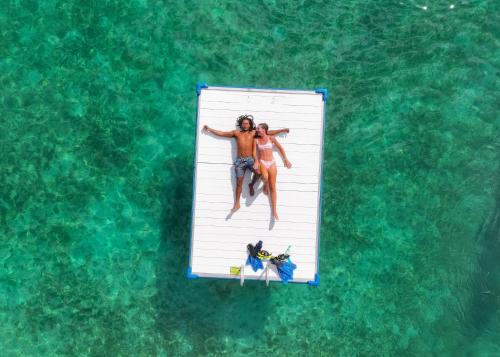 a man and woman laying on a dock in the water at Secret Harbour Beach Resort in St Thomas