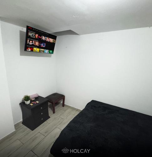 a bedroom with a bed and a tv on the wall at Hospedaje Holcay in Bogotá