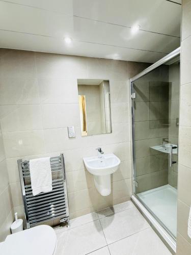 a white bathroom with a sink and a shower at Sandyford Lodge in Glasgow